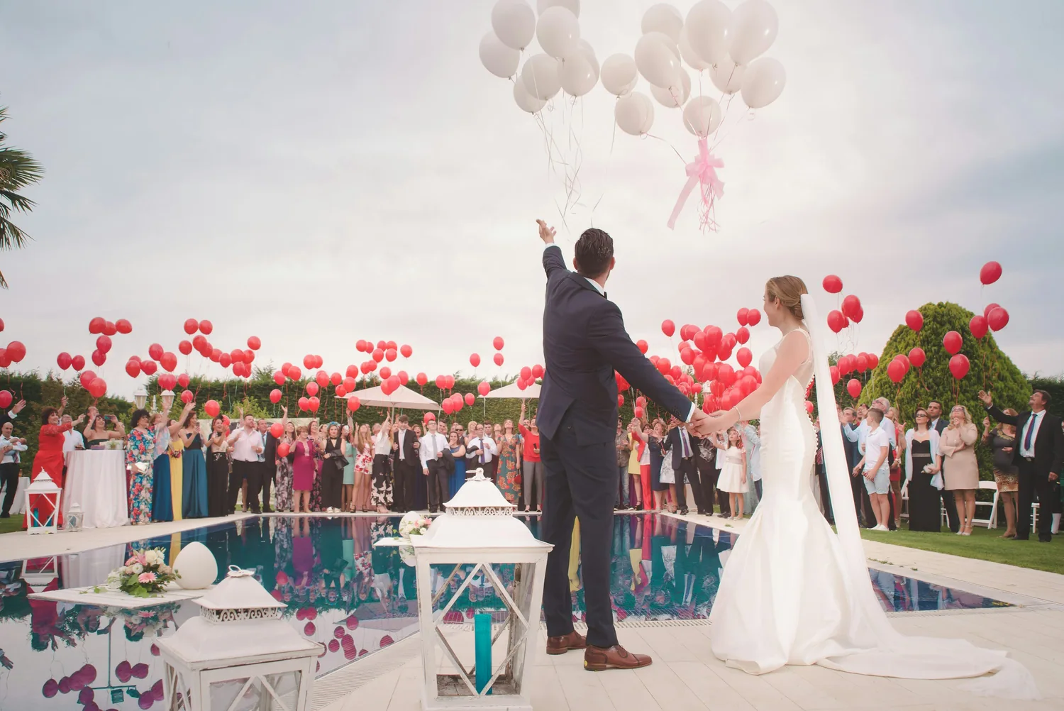 A couple and their guests releasing balloons outdoors