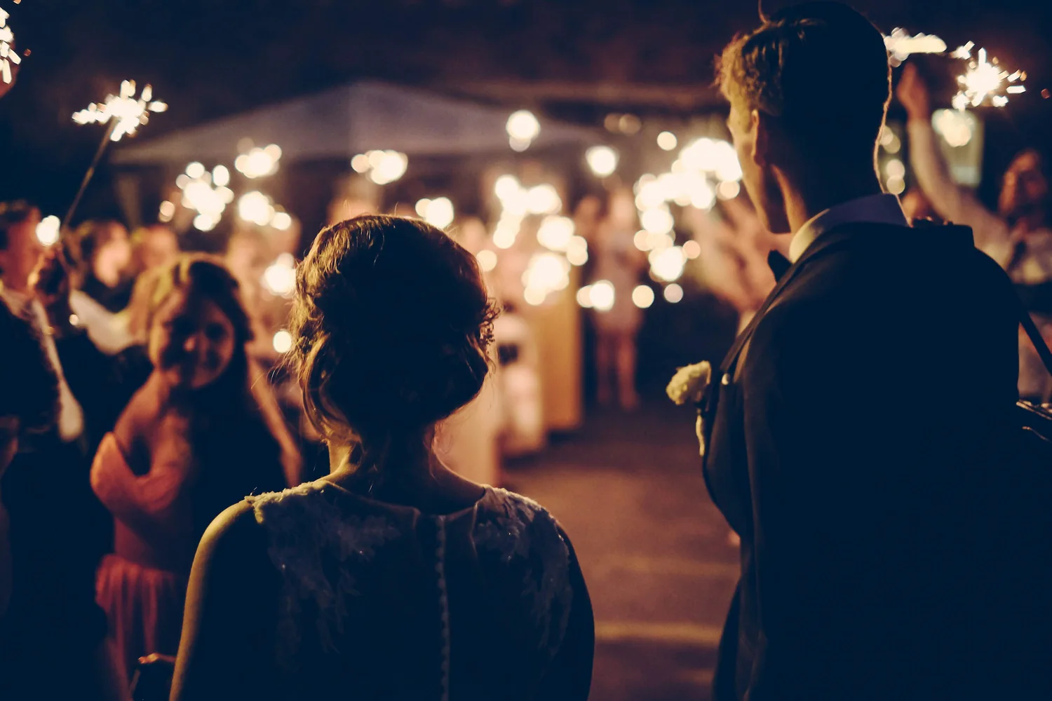 Guests holding glowing sparklers under the night sky