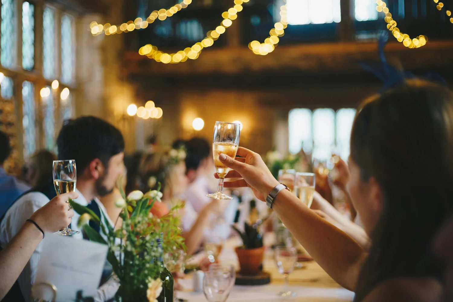 A guest raising a glass at a warmly lit wedding table