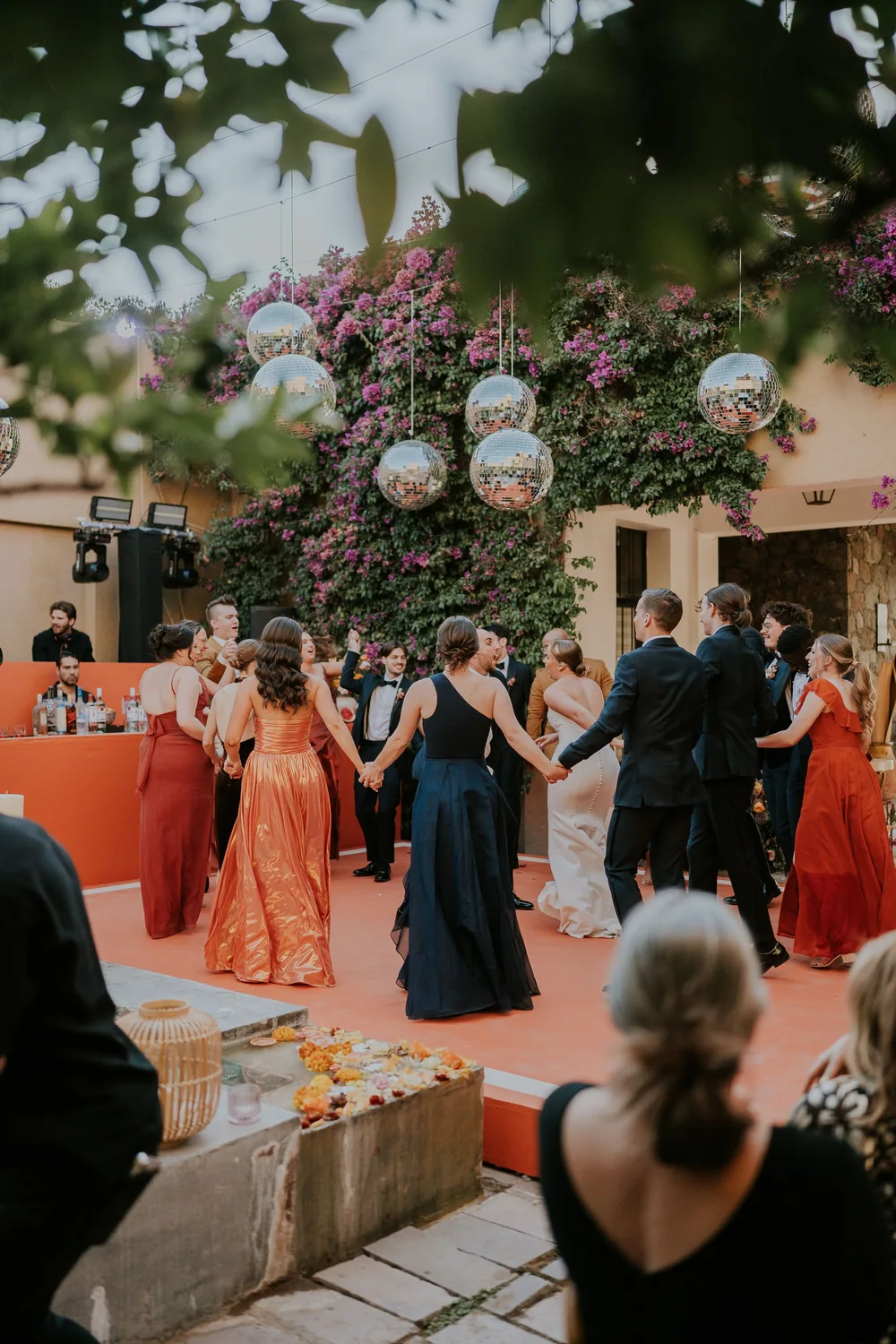 Guests dancing at an outdoor wedding beneath flowers and disco balls